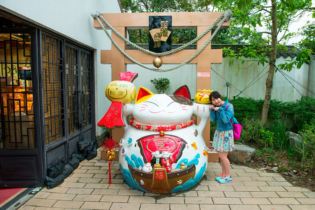 Junges asiatisches Mädchen vor kitschiger Figur, Hongkong, Hong Kong, Asien
