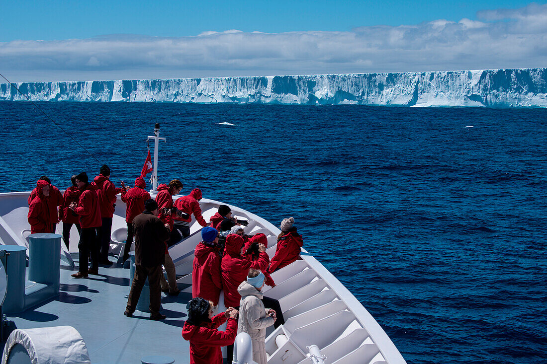 Passagiere am Bug von Expeditions-Kreuzfahrtschiff MS Hanseatic (Hapag-Lloyd Kreuzfahrten) vor riesigem Eisberg, nahe Shag Rocks, Südlicher Atlantischer Ozean zwischen Falklandinseln und Südgeorgien, Antarktis
