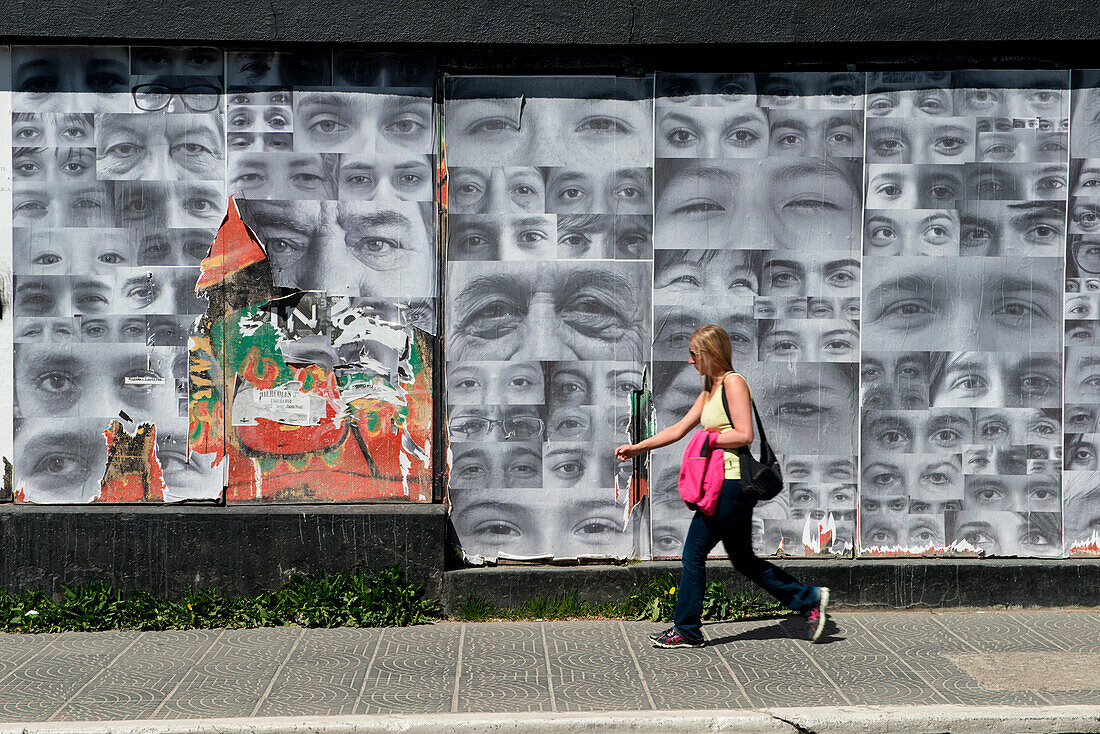 Frau läuft entlang Wandgemälde mit vielen Bildern von Augen, Ushuaia, Feuerland, Patagonien, Argentinien, Südamerika