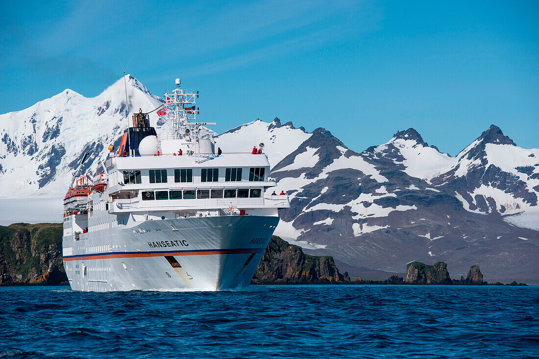 Expedition cruise ship MS Hanseatic (Hapag-Lloyd Cruises) and snow-covered mountain backdrop, Prion Island, near South Georgia Island, Antarctica