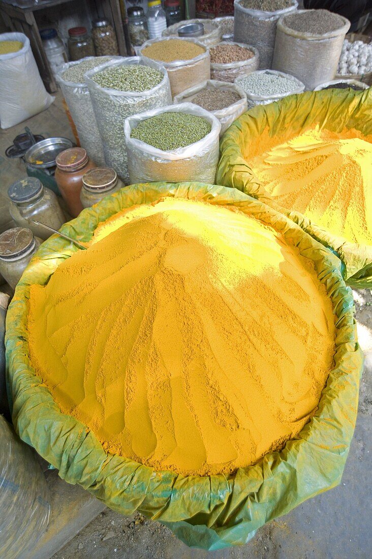 Spice market stall with large bowls of turmeric powder in early morning market on the banks of the Brahmaputra river, Guwahati, Assam, India, Asia