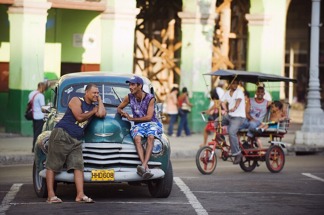 Men relaxing on a 1950s classic American car, Central Havana, Cuba, West Indies, Caribbean, Central America