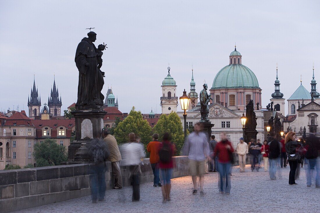 Statues and crowd on Charles Bridge, UNESCO World Heritage Site, with the dome of the church of St. Francis beyond, evening light, Old Town, Prague, Czech Republic, Europe