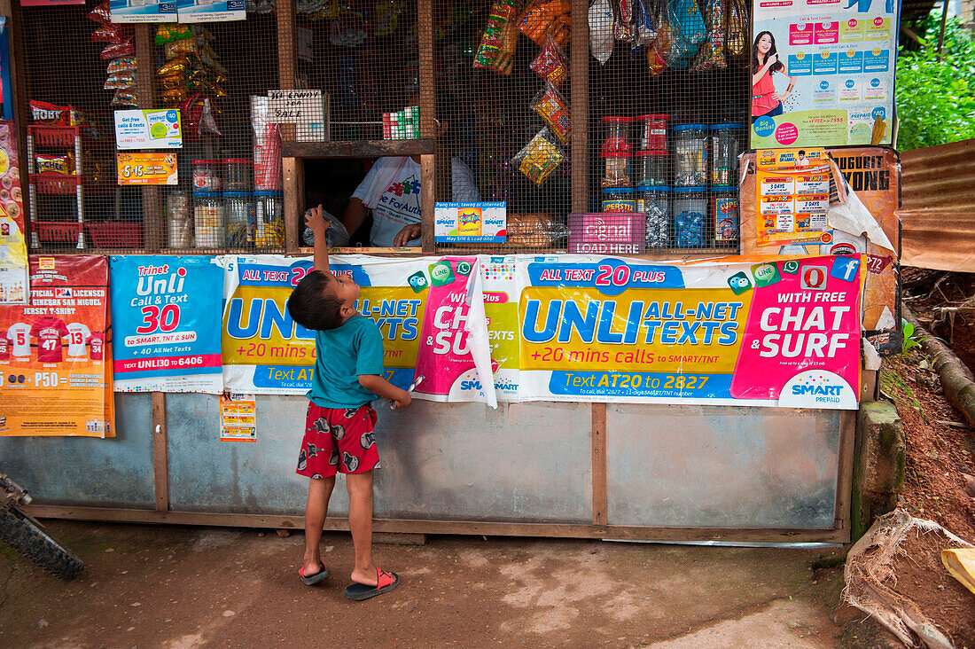 Young boy reaches for the top at grocery shop, Coron, Busuanga, Palawan, Philippines, Asia