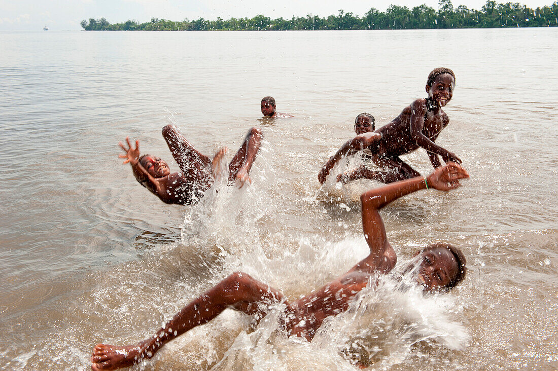 Fröhliche Kinder schwimmen und planschen im Meer, Kopar, East Sepik Provinz, Papua-Neuguinea, Südpazifik