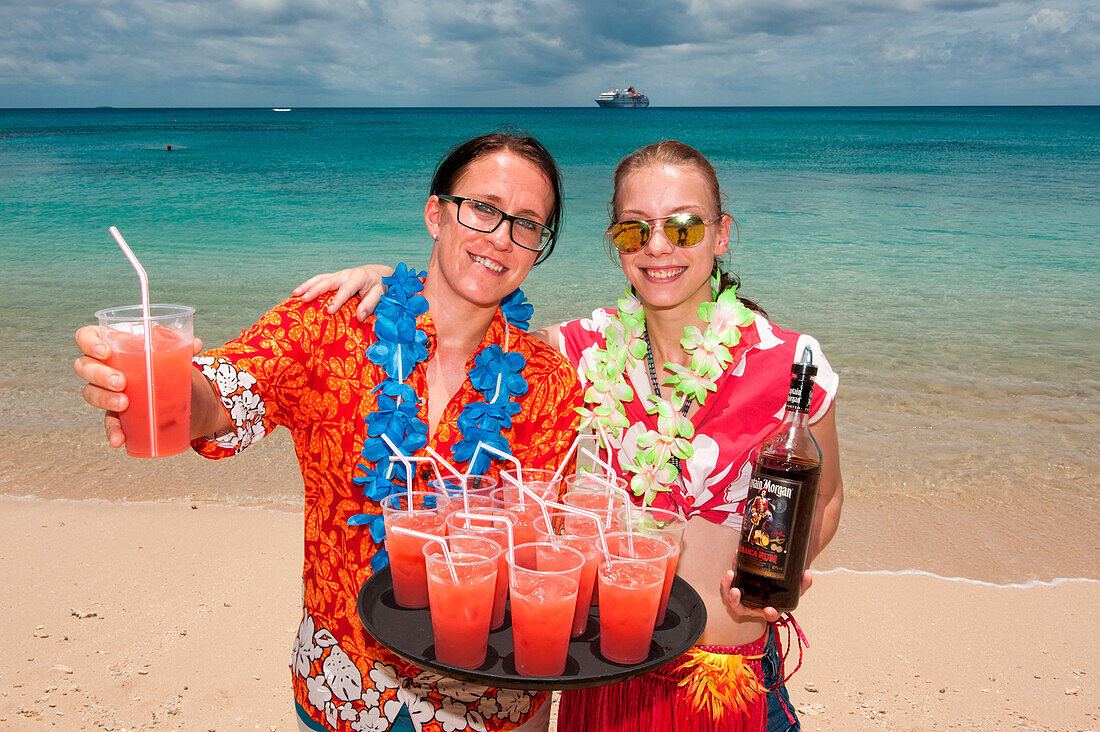 Fröhliche Kellnerinnen vom Expeditions-Kreuzfahrtschiff MS Hanseatic (Hapag-Lloyd Kreuzfahrten) servieren tropische Cocktails am Strand des Sandy Beach Resort, Insel Foa, Ha'apai Gruppe, Tonga, Südpazifik