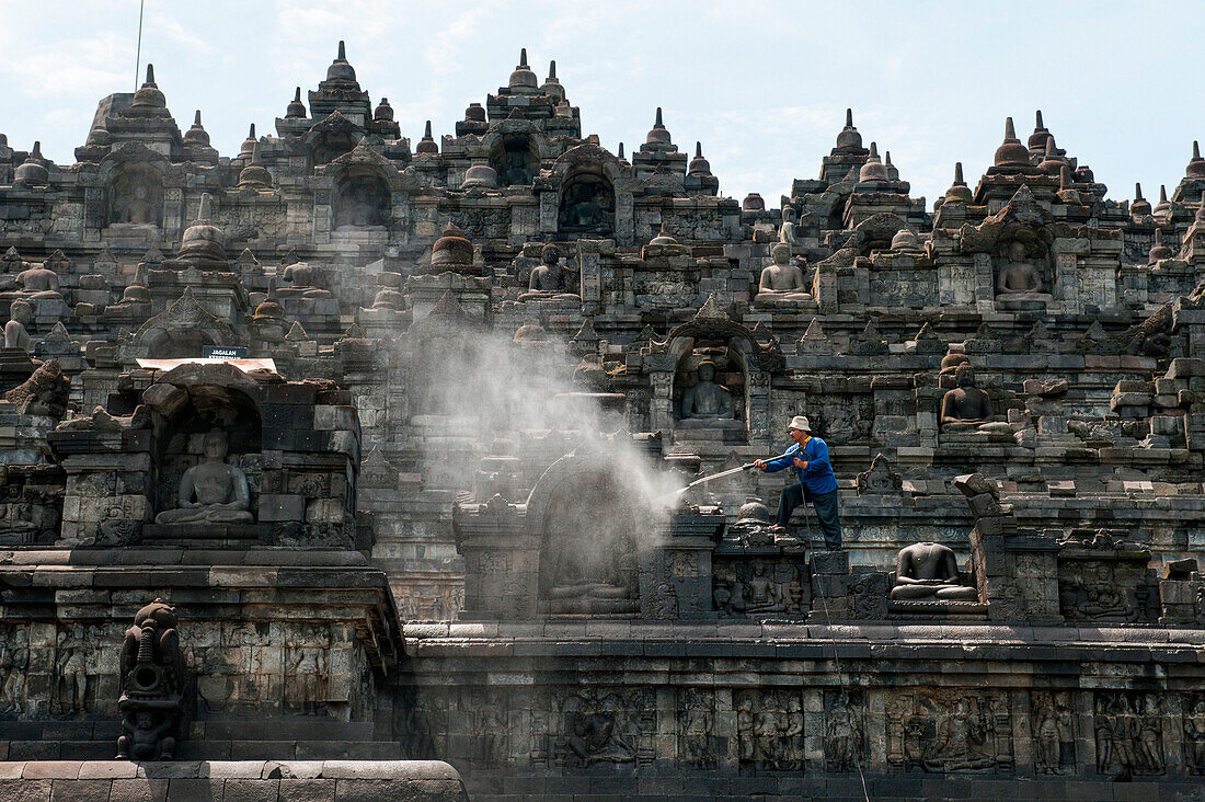 Mann reinigt Steine an der buddhistischen Tempelanlage Borobodur, Borobodur, Zentraljava, Java, Indonesien, Asien