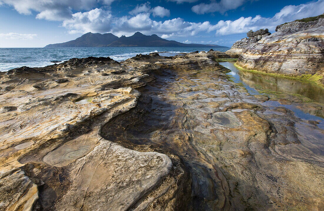 View towards Isle of Rum from rock formations at Laig Bay, Isle of Eigg, Inner Hebrides, Scotland, United Kingdom, Europe