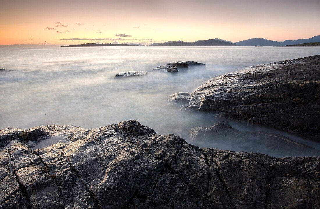 Dusk view across open water towards Taransay and North Harris from the rocky shore at Borve, Isle of Harris, Outer Hebrides, Scotland, United Kingdom, Europe