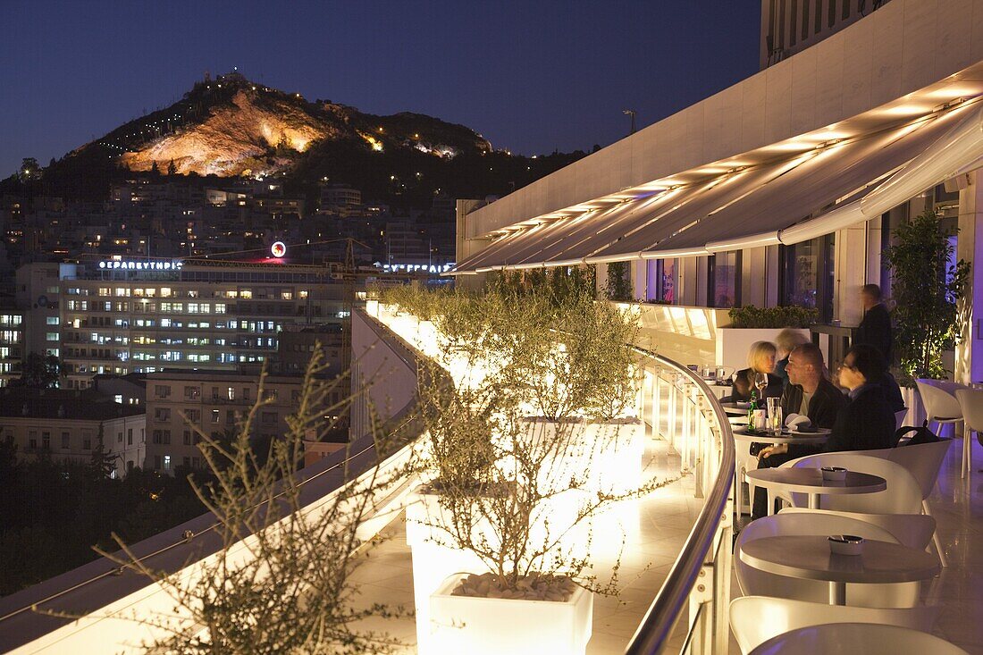 Rooftop terrace bar at the Athens Hilton with Lykavittos Hill illuminated at night, Athens, Greece, Europe