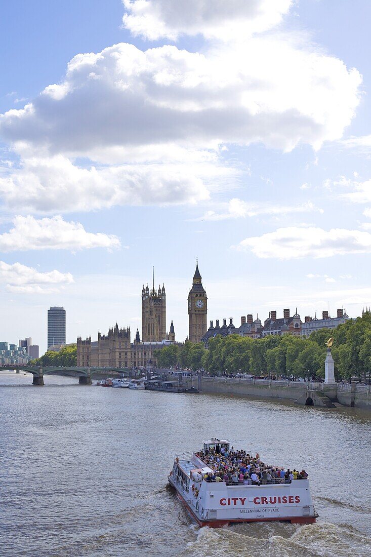 Tourist cruise boat on the River Thames and the Houses of Parliament in the distance, London, England, United Kingdom, Europe