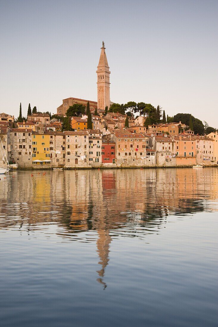 The Cathedral of St. Euphemia and Venetian style buildings in Rovinj reflected in the sea at sunrise, Rovinj, Istria, Croatia, Europe