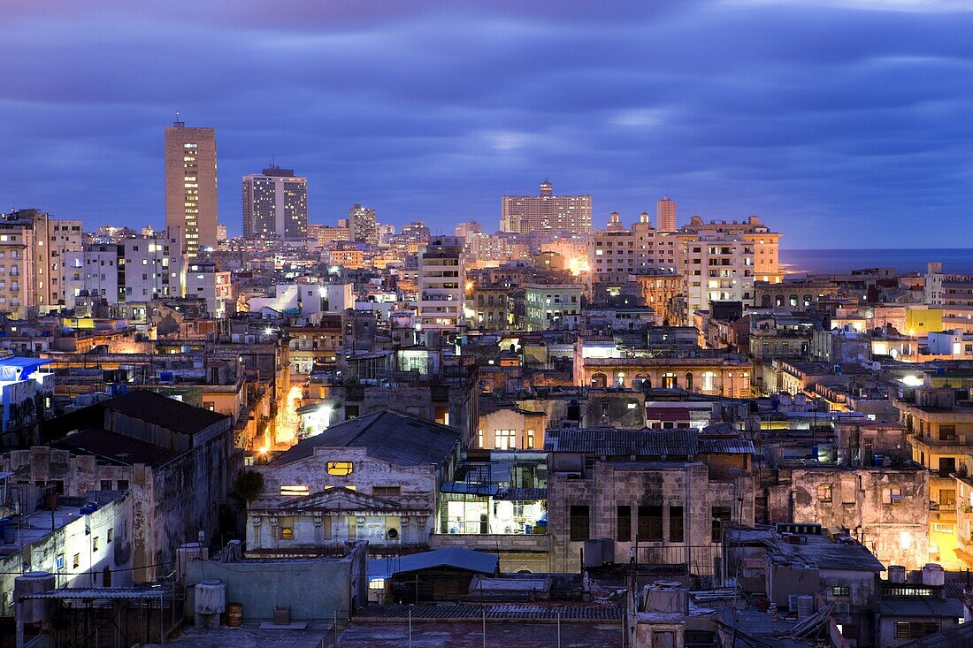 View over Havana Centro at night from Hotel Seville showing contrast of old, semi-derelict apartment buildings against a backdrop of more modern, affluent architecture, Havana, Cuba, West Indies, Central America