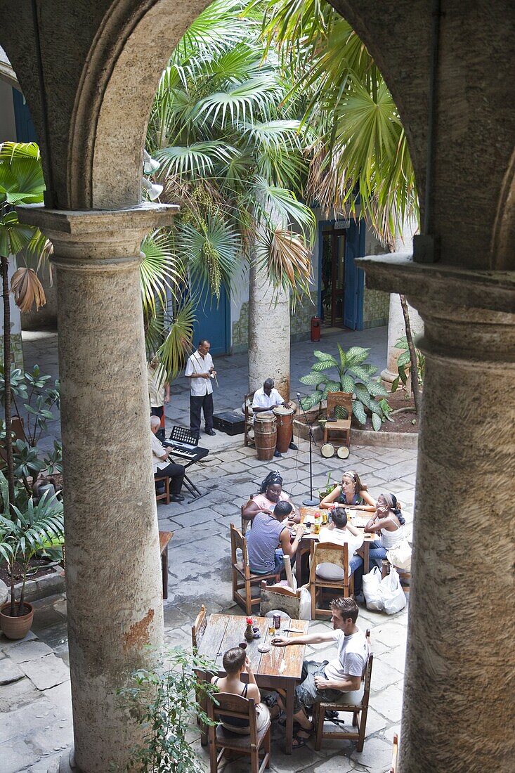 People sitting at tables and musicians playing in courtyard of colonial building built in 1780, Havana, Cuba, West Indies, Central America