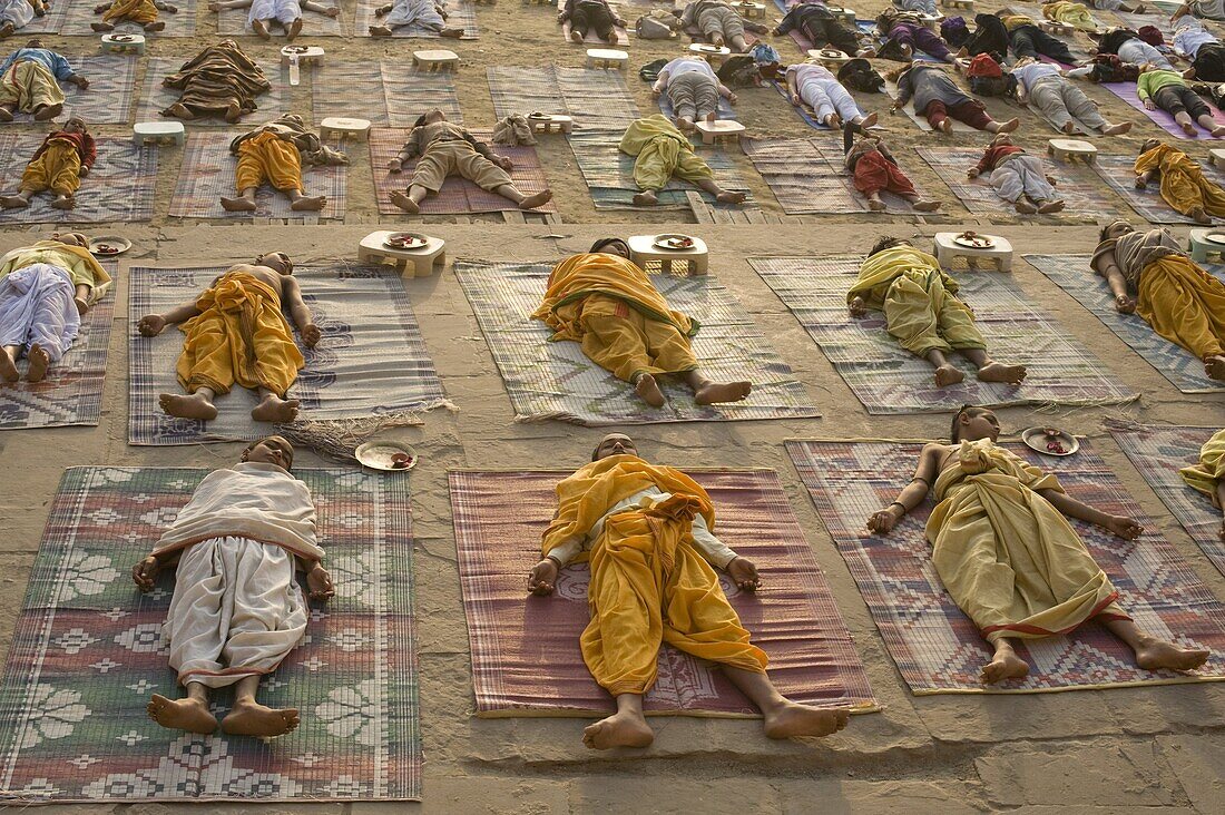 Students of a Sanskrit school performing the savasana (corpse) posture during daily yoga lesson at sunrise, on the ghat of Varanasi, Uttar Pradesh, India, Asia