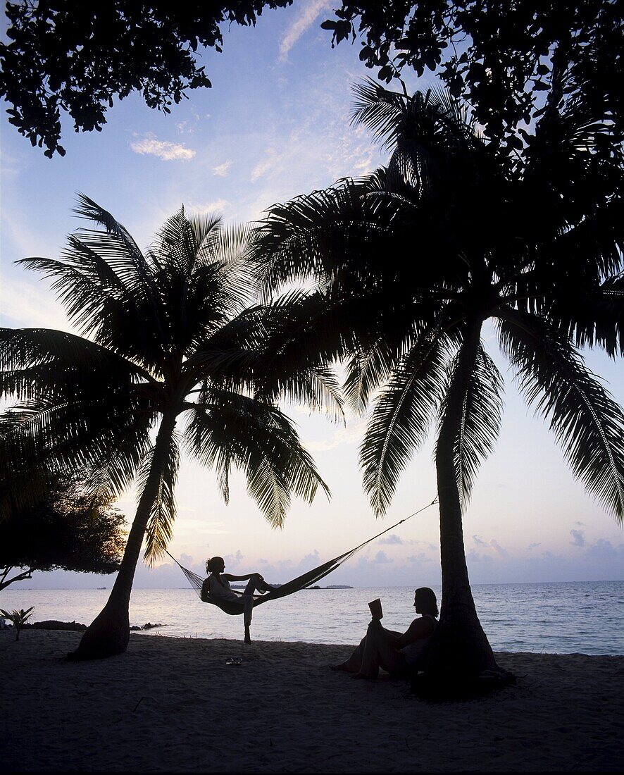 Couple relaxing on a beach at sunset, Maldives, Indian Ocean, Asia