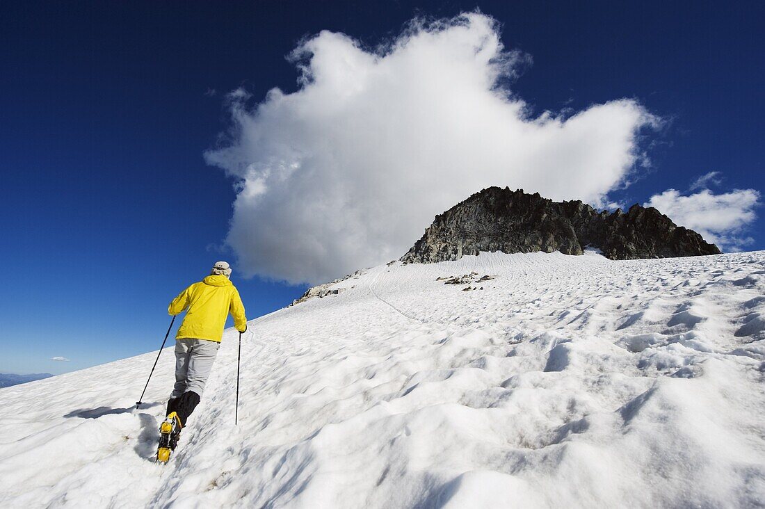 A climber walking up a snowfield, Pico de Aneto, at 3404m the highest peak in the Pyrenees, Spain, Europe