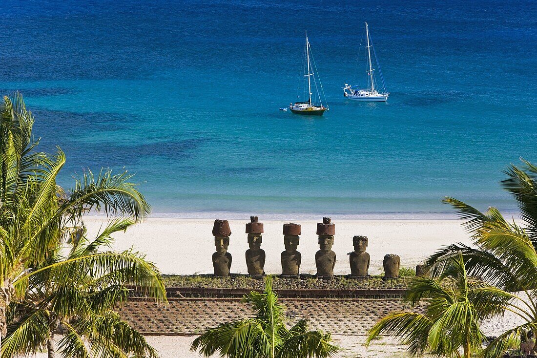 Anakena beach,  yachts moored in front of the monolithic giant stone Moai statues of Ahu Nau Nau,  four of which have topknots,  Rapa Nui (Easter Island),  UNESCO World Heritage Site,  Chile,  South America