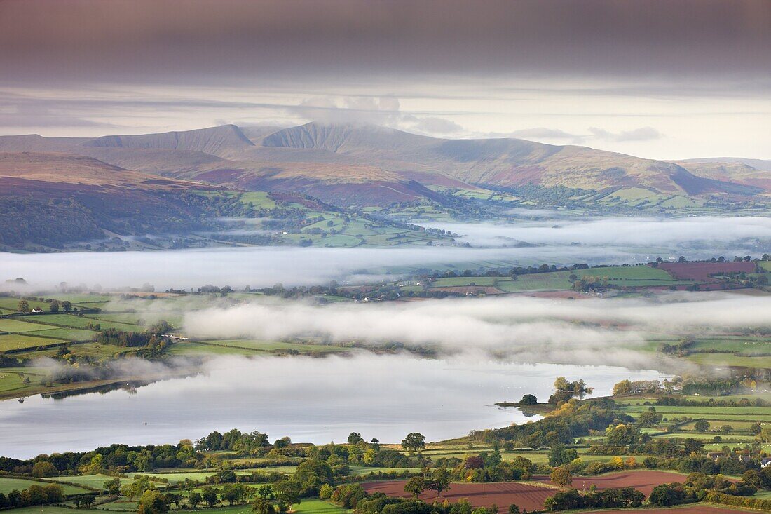 Pen Y Fan rises above a mist shrouded landscape near Llangorse Lake,  Brecon Beacons National Park,  Powys,  Wales,  United Kingdom,  Europe