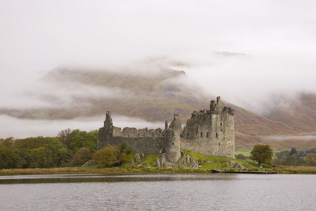 View across Loch Awe to the ruins of Kilchurn Castle, early morning mist on mountains, Dalmally, Argyll and Bute, Scotland, United Kingdom, Europe