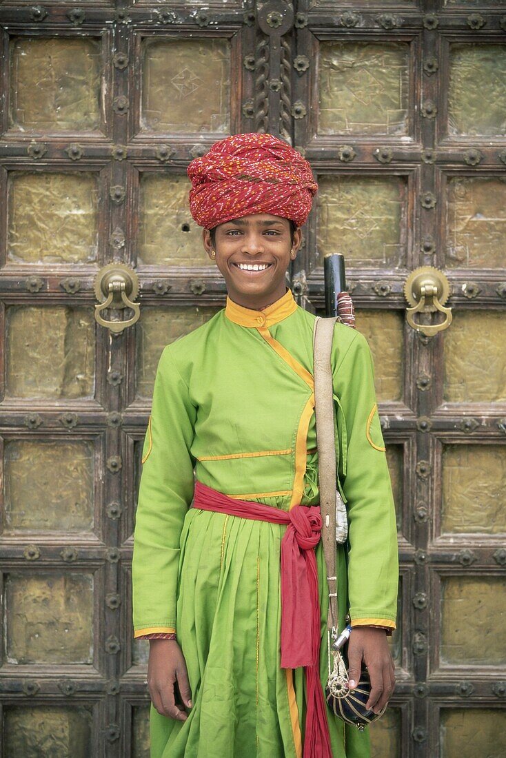 Portrait of a boy in a turban standing in front of a wooden door, Samode Palace, Jaipur, Rajasthan state, India, Asia