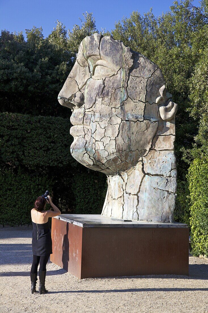 Young woman taking photograph of the Monumental Head, by Igor Mitora, Boboli Gardens, Florence, Tuscany, Italy, Europe
