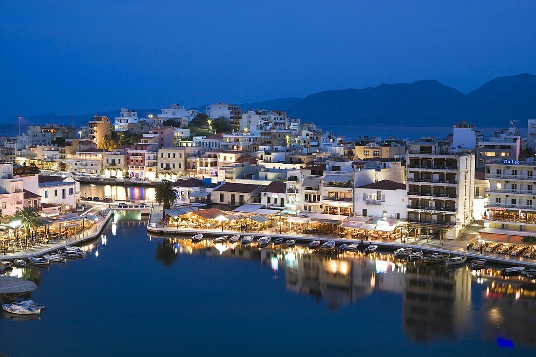 View over harbour and restaurants at dusk, Ayios Nikolaos, Lasithi region, Crete, Greek Islands, Greece, Europe