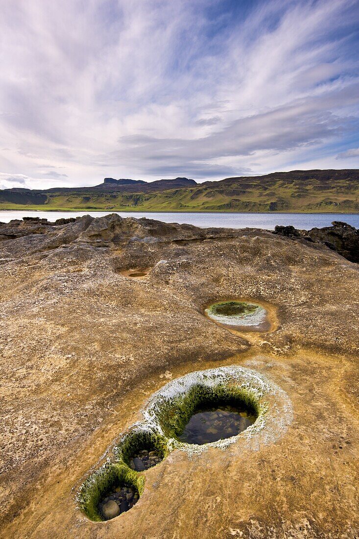 Rock pools beyond Laig Bay with An Sgurr in the distance, Isle of Eigg, Inner Hebrides, Scotland, United Kingdom, Europe