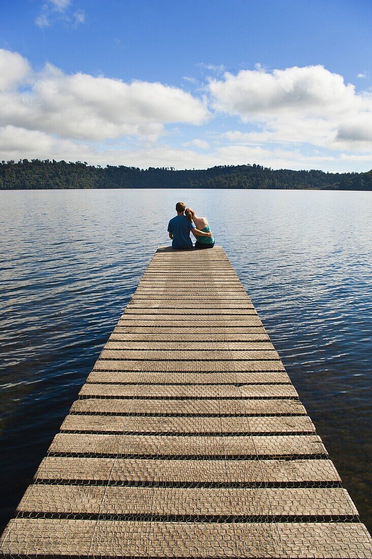 Couple on holiday sitting together at romantic Lake Ianthe, South Island, New Zealand, Pacific