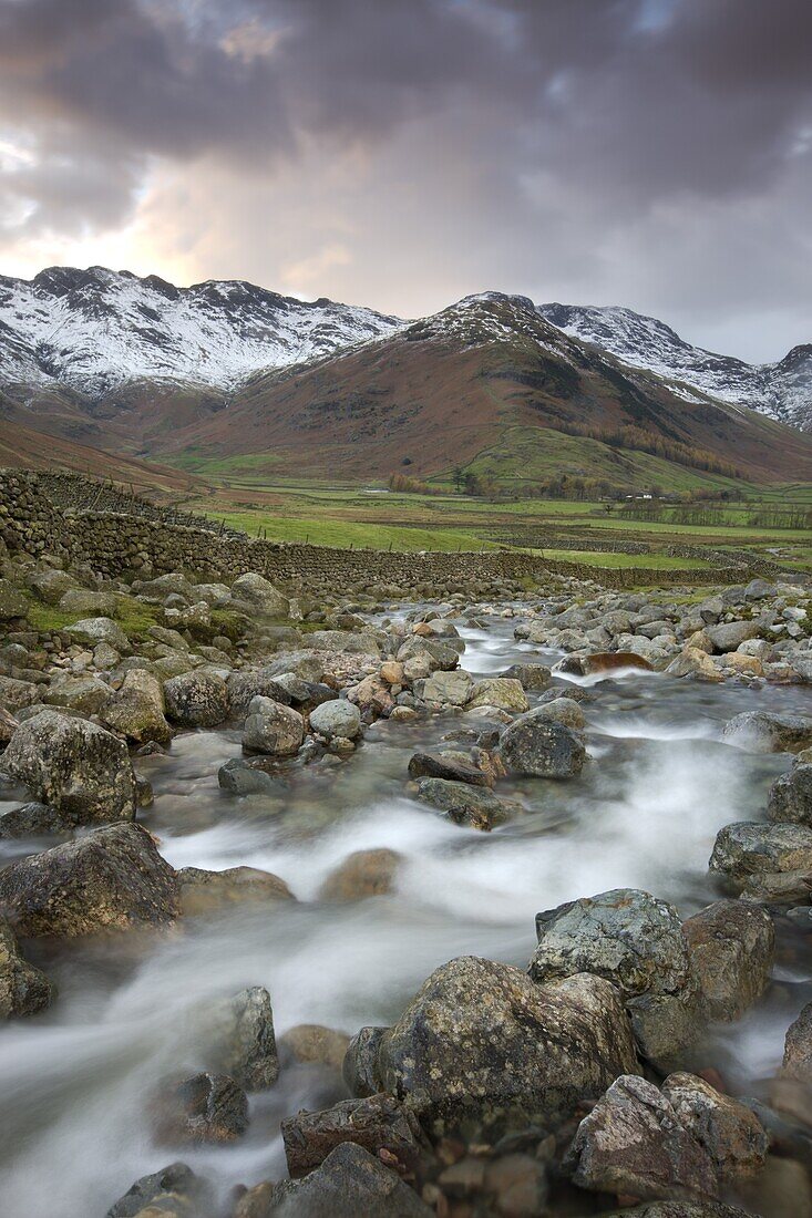 Redacre Gill river tumbling over rocks towards the snow capped mountains surrounding Great Langdale, Lake District National Park, Cumbria, England, United Kingdom, Europe
