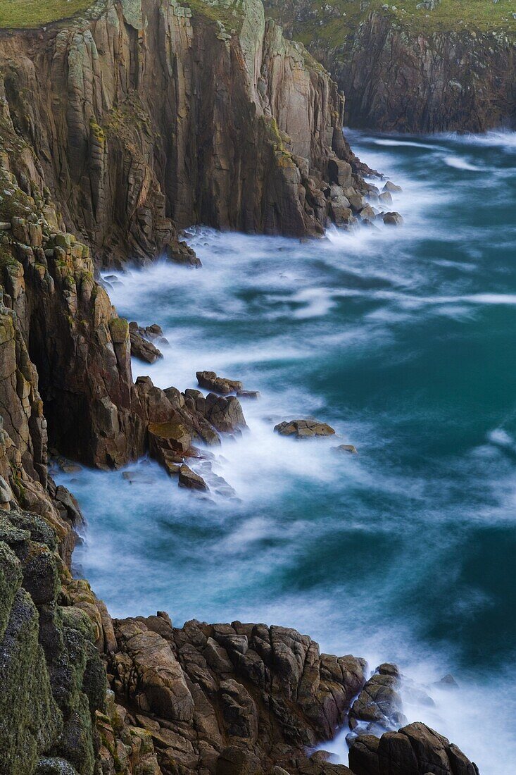 The Atlantic Ocean crashes around the base of the huge Lands End cliffs, Cornwall, England, United Kingdom, Europe