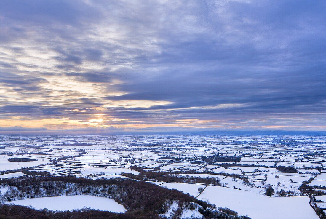 Sinking sun and stormy clouds over a snow covered Gormire Lake from Sutton Bank on the edge of the North Yorkshire Moors, Yorkshire, England, United Kingdom, Europe