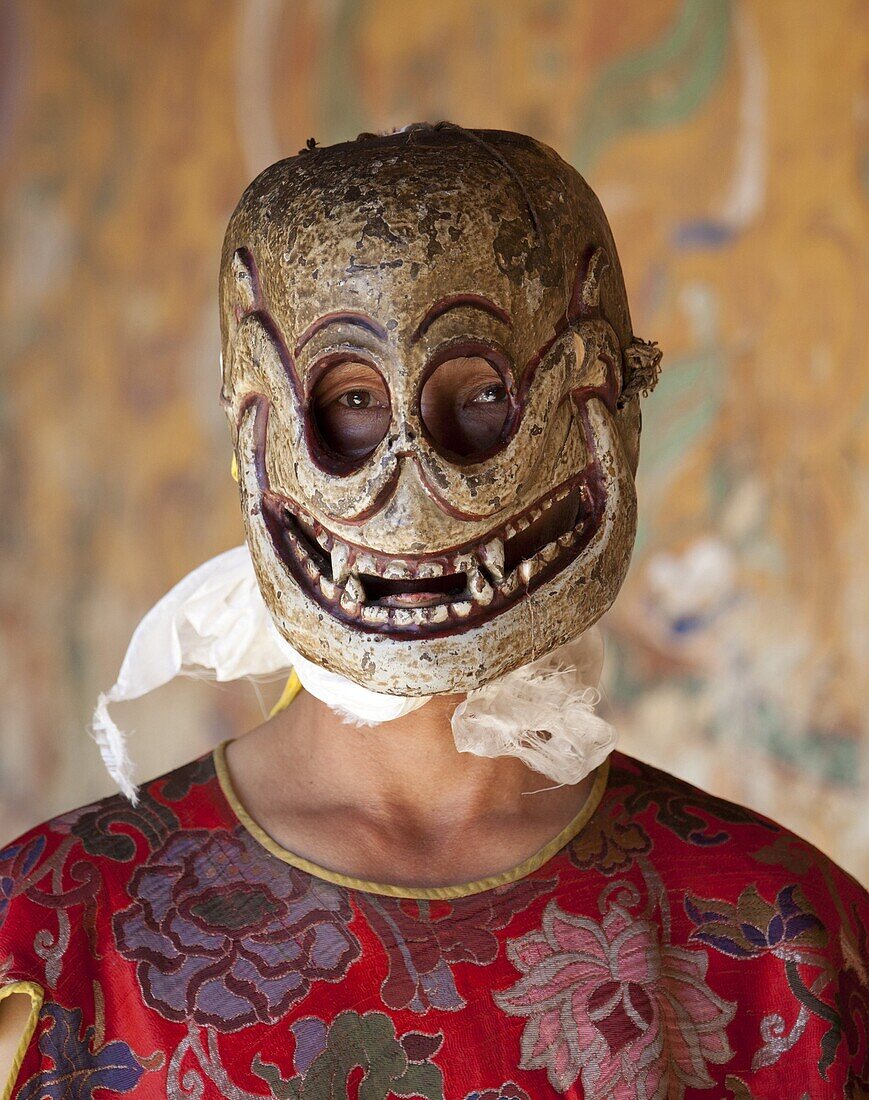 Buddhist monk wearing carved wooden mask in the shape of a skull preparing to take part in traditional dance performance at the Tamshing Phala Choepa Tsechu, near Jakar, Bumthang, Bhutan, Asia