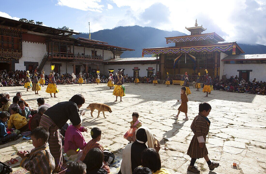 Masked dance in the main courtyard of the Gangte Goemba while local people and tourists watch during the Gangtey Tsechu, Gangte, Phobjikha Valley, Bhutan, Asia