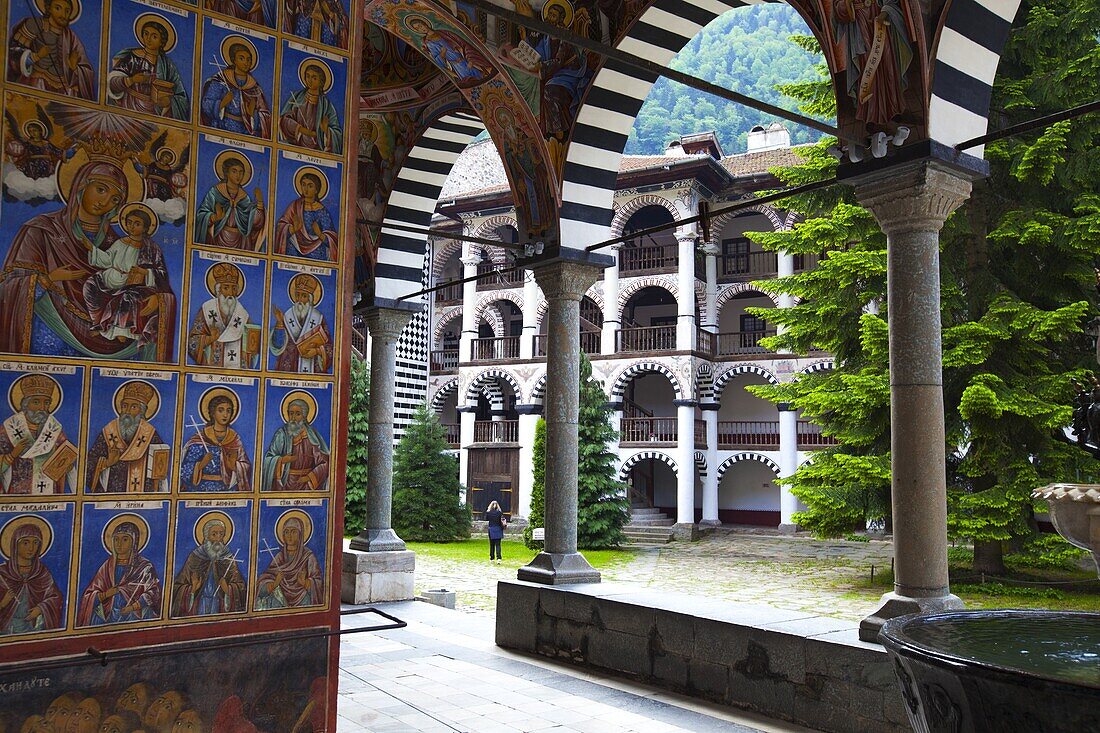 Bulgaria, Rila Monastery nestled in the Rila Mountains, Courtyard, Church of the Nativity, Arcade Murals depicting Religious figures.