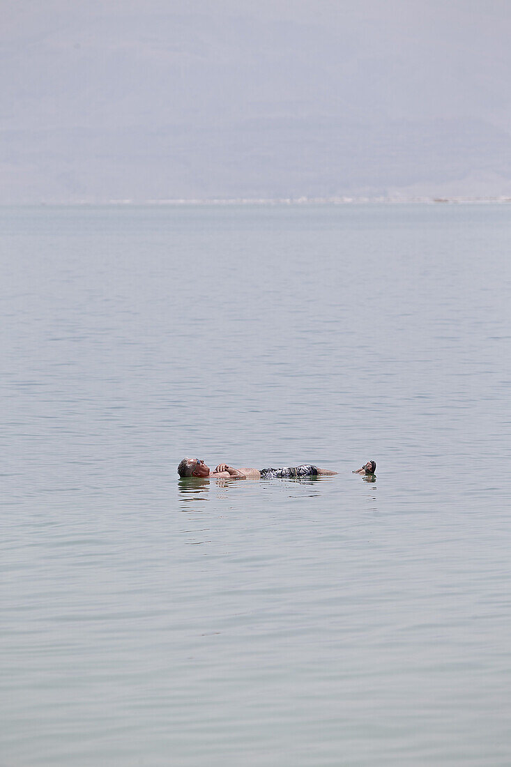 Mann liegt im Wasser des Toten Meeres, Masada, Totes Meer, Israel