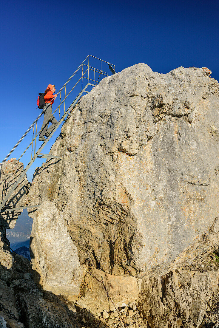 Frau beim Wandern steigt auf Leiter auf La Tournette, La Tournette, Hochsavoyen, Frankreich