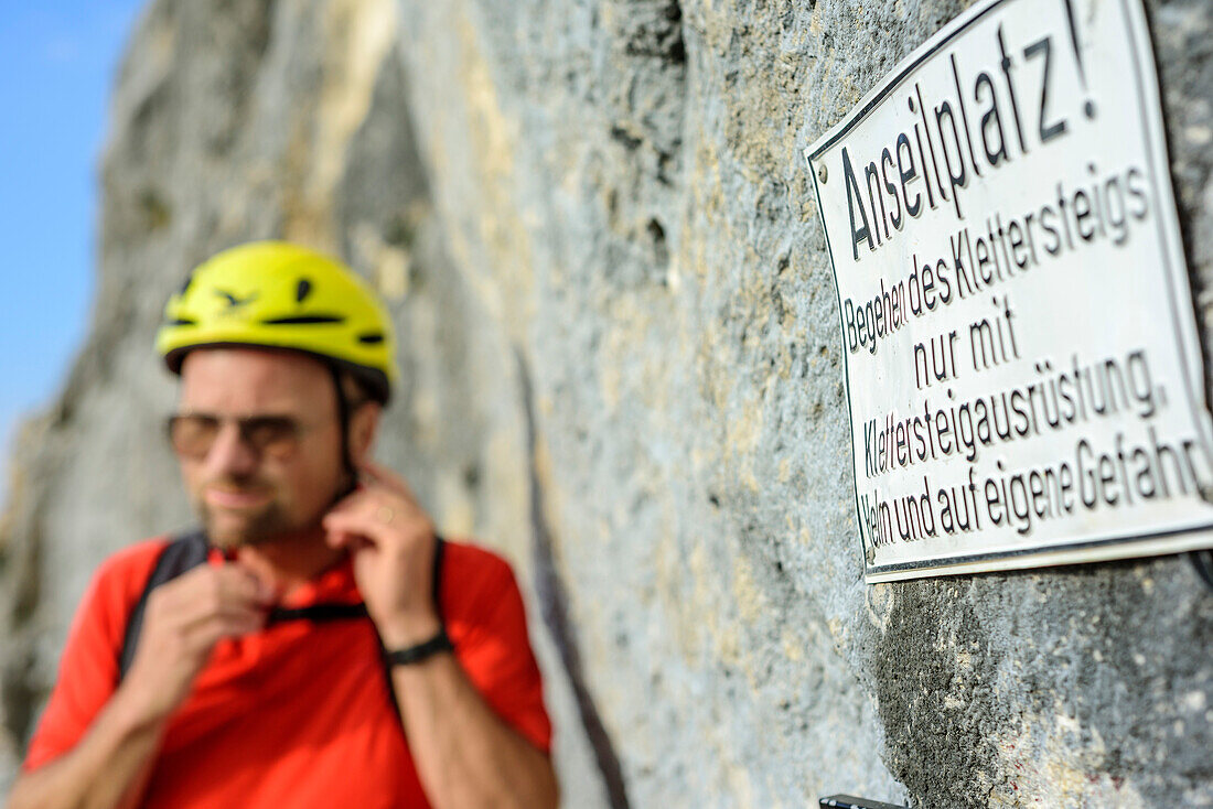 Man hiking putting on helmet, Hochthronklettersteig, fixed rope route Hochthron, Untersberg, Berchtesgadener Hochthron, Berchtesgaden Alps, Upper Bavaria, Bavaria, Germany