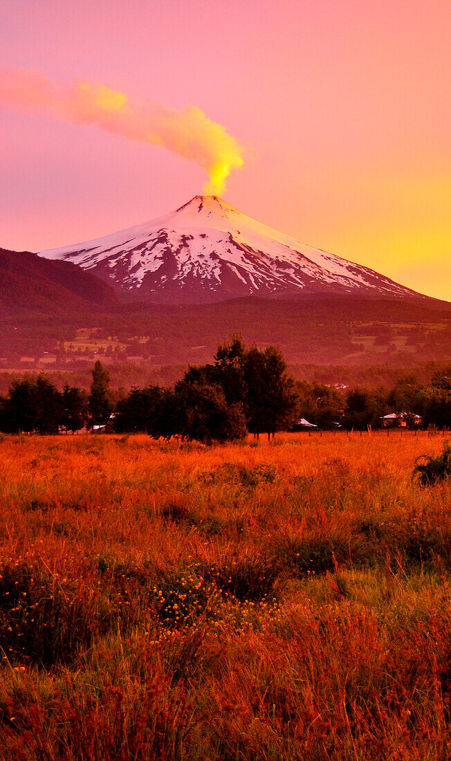 Volcano Villarrica at sunset, snow covered with smoke signalizing soon volcanic outburst and eruption, Strato volcano, sunset, National Park Villarrica, Pucon, Región de la Auracania, Region Los Rios,  Patagonia, Andes, Chile, South America