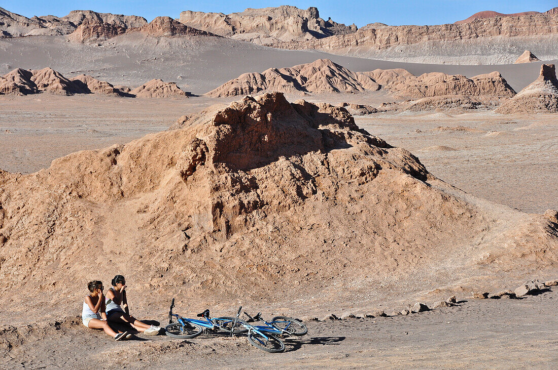 'Junge Frauen mit Fahhrädern zwischen Felsen, Valle de la Luna, Tal des Mondes, Atacama Wüste, Reserva Nacional Los Flamencos, Region de Antofagasta, Anden, Chile, Südamerika, Amerika;'