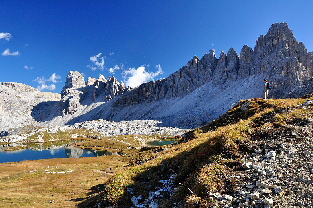 Hiking woman beneath Paternkofel and at lakes Zinnenseen, Val Pusteria Valley, Sesto, Dolomites, South Tyrol, Veneto, Alto Adige, Three Peaks (Tre Cime di Lavaredo) Nature Park, UNESCO world heritage side, Italy, European Alps, Europe