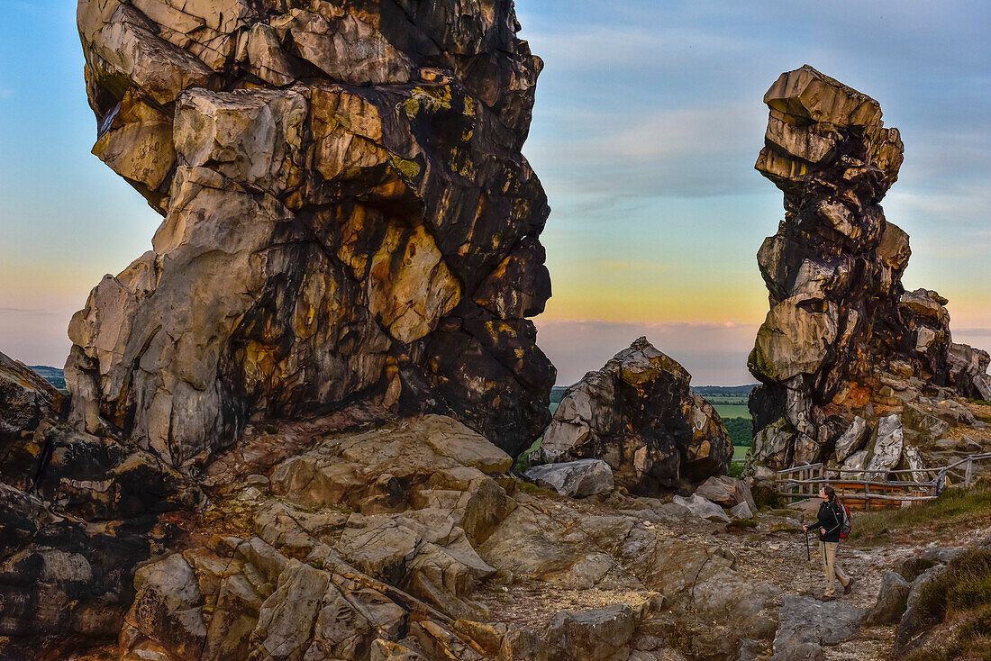 Junge Frau wandert entlang der Felsformation Teufelsmauer bei Sonnenuntergang, Neinstedt, Thale, Harzvorland, Harz, Sachsen-Anhalt, Deutschland