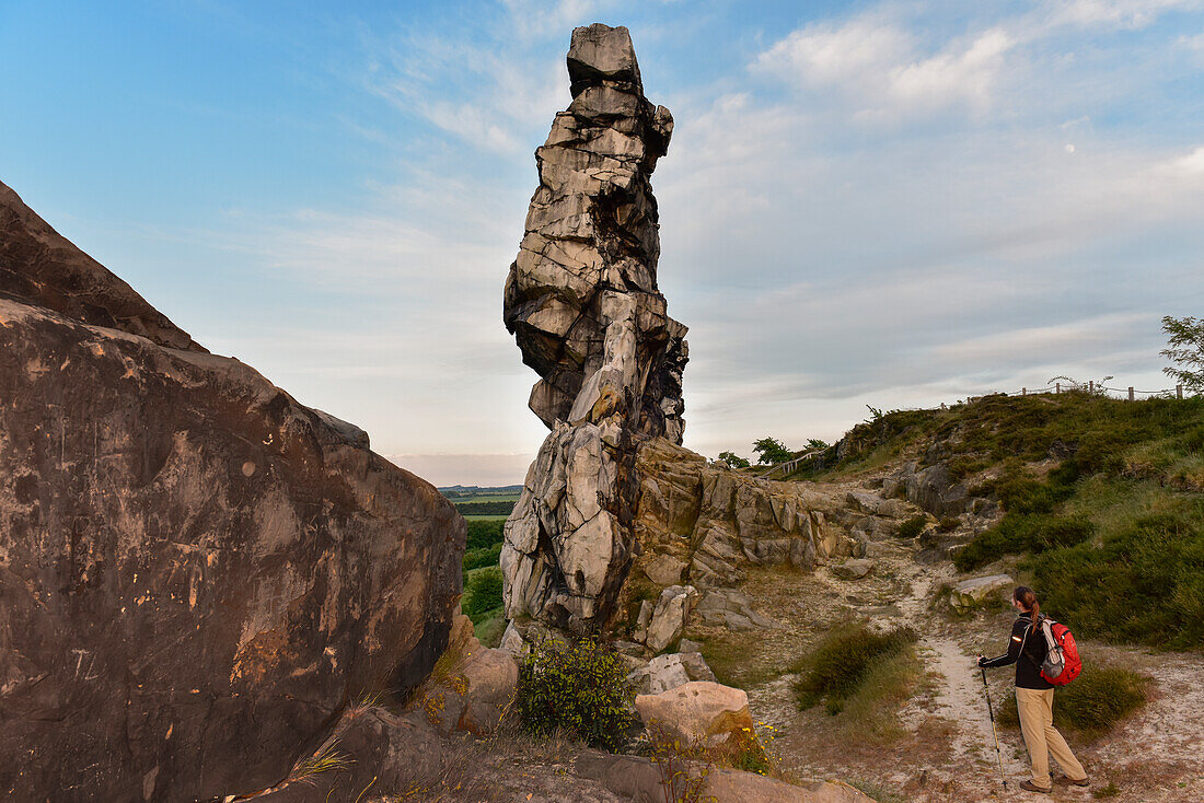 Junge Frau wandert entlang der Felsformation Teufelsmauer bei Sonnenuntergang, Neinstedt, Thale, Harzvorland, Harz, Sachsen-Anhalt, Deutschland