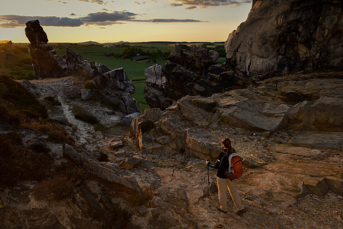 Young woman is hiking along rock formation Devil´s Wall (Teufelsmauer) at sunset, Neinstedt, Thale, Harz Foreland, Harz Mountains, Saxony-Anhalt, Germany