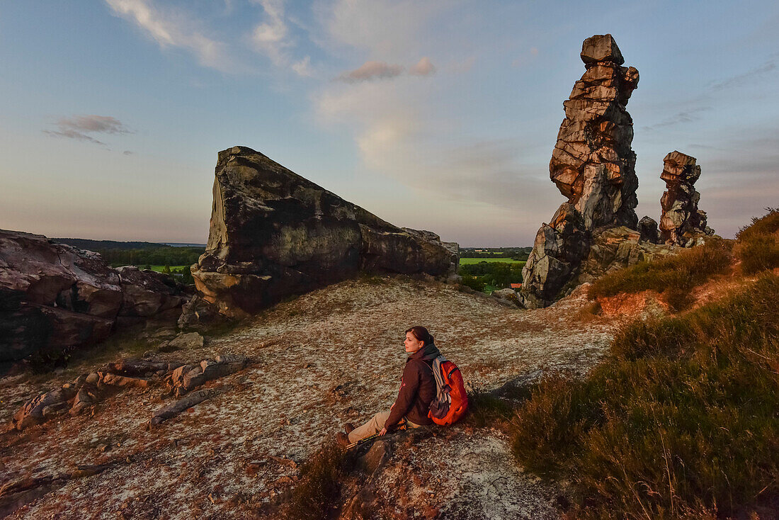 Junge Frau wandert entlang der Felsformation Teufelsmauer bei Sonnenuntergang, Neinstedt, Thale, Harzvorland, Harz, Sachsen-Anhalt, Deutschland