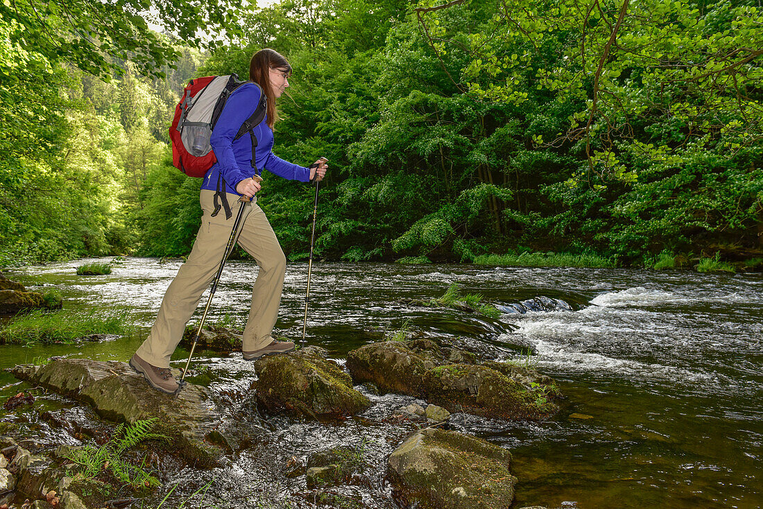 Junge Frau wandert auf Steinen am Fluß Bode im Bodetal auf dem Wanderweg Harzer Hexen Stieg von Thale nach Treseburg, Frühjahr, Harzvorland, Harz, Sachsen-Anhalt, Deutschland