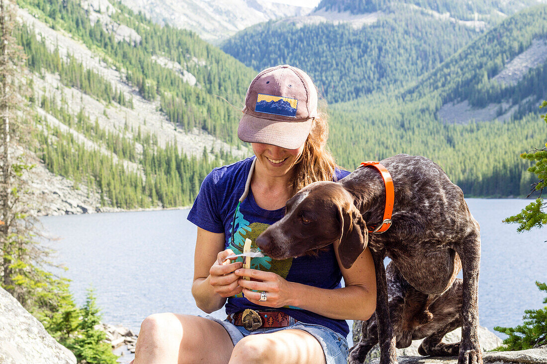 Woman shares her string cheese with her dog while on a hike in Montana
