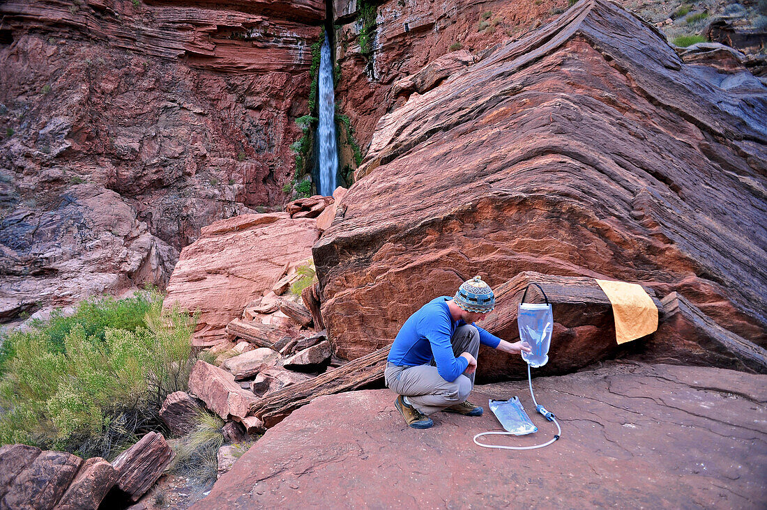Male hiker filters water on a cliff-pinched patio near Deer Creek Falls in the Grand Canyon outside of Fredonia, Arizona November 2011.  The 21.4-mile loop starts at the Bill Hall trailhead on the North Rim and descends 2000-feet in 2.5-miles through Coco