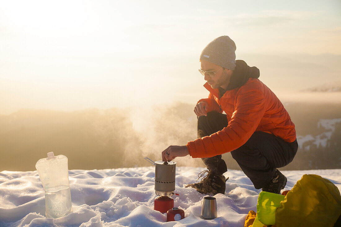 A climber attends to his boiling water on a camping stove while camping in the mountains of British Columbia, Canada.