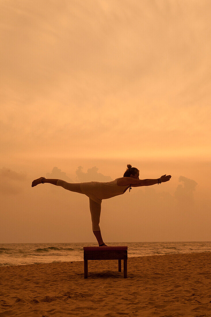 Girl doing yoga at sunset on the beach in Sri Lanka